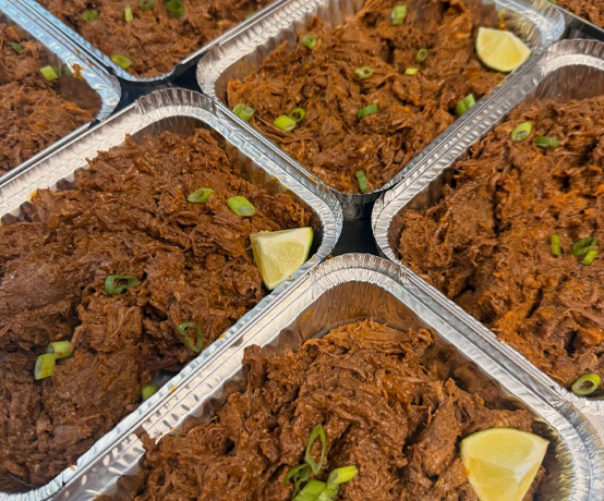 Foil pans of shredded beef with lime wedges